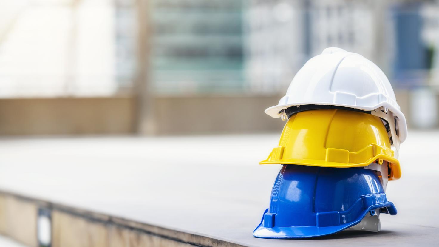 3 hard hats sit on a concrete floor