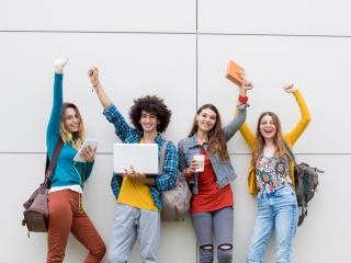 4 young people smiling at the camera and raising their fists