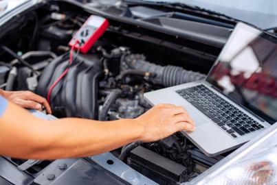 Meccanico uomo che utilizza il computer portatile esaminando la messa a punto di fissaggio riparazione auto